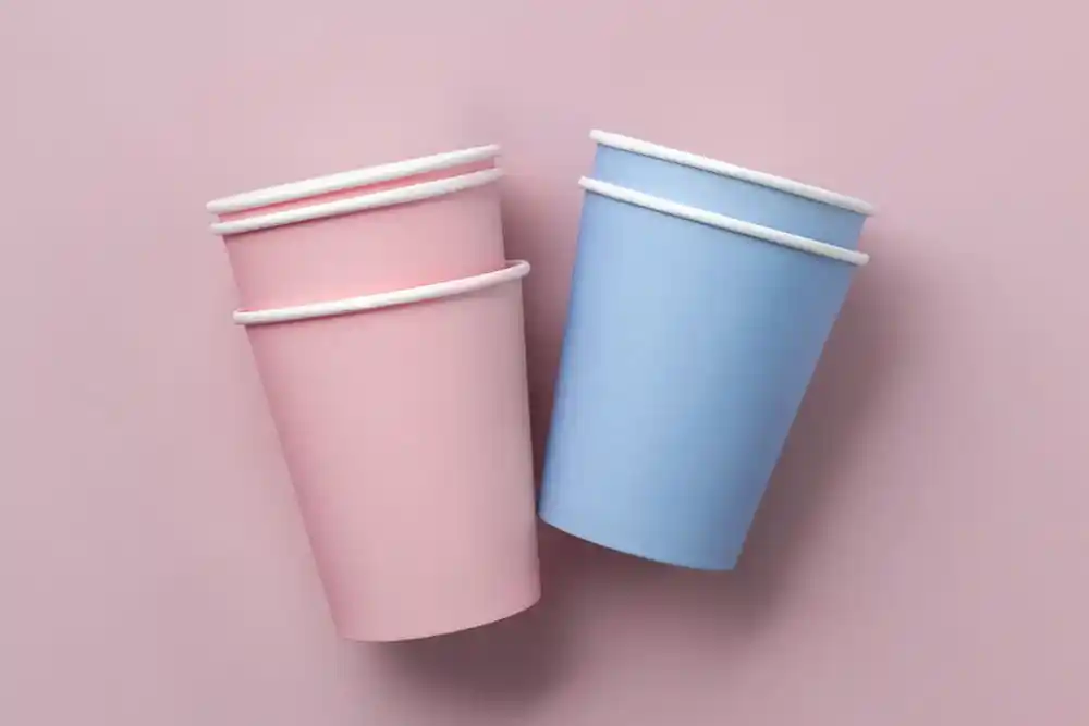 Pembe ve mavi, beyaz kenarlı iki kâğıt bardak