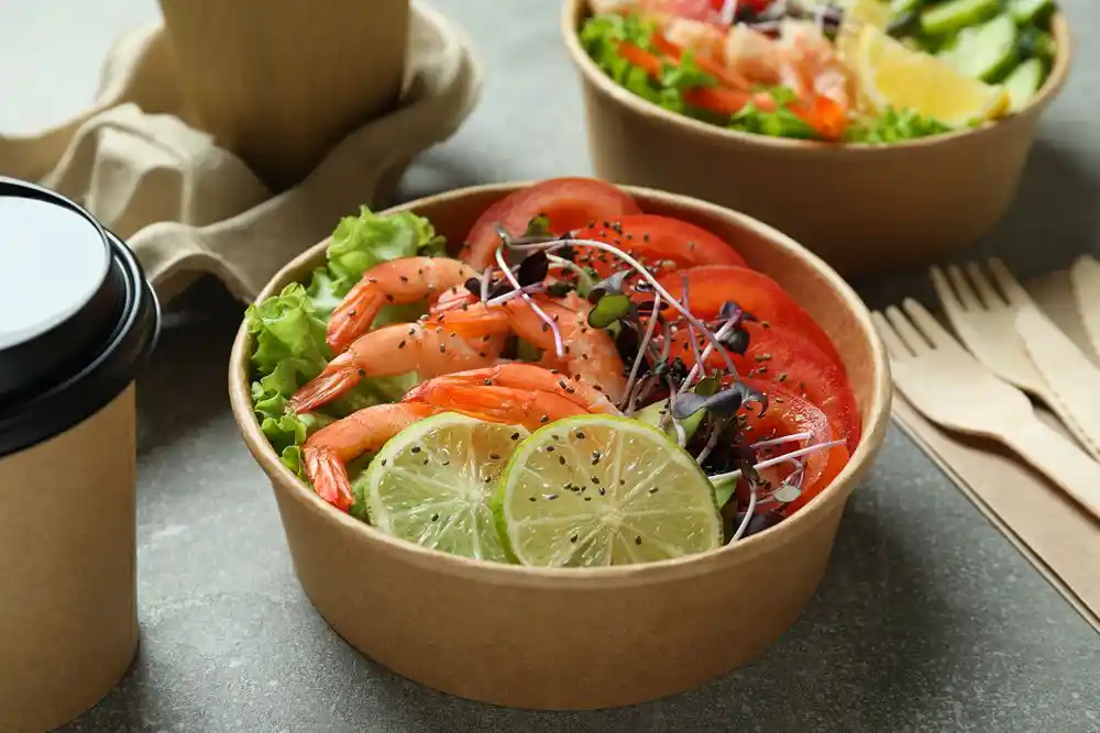 Karides, domates, marul, filizler ve limon dilimleri içeren salata kasesi